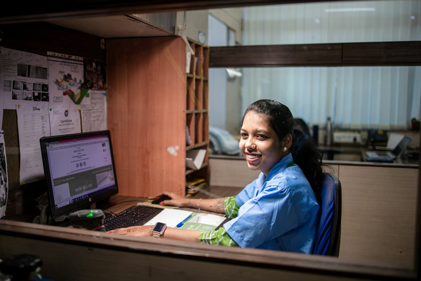 Mujer con uniforme azul trabajando en su computadora de oficina.
